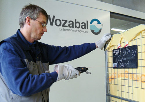 Bild von einem Wozabal Mitarbeiter beim Scannen des Barcodes auf einem Wäschecontainer
